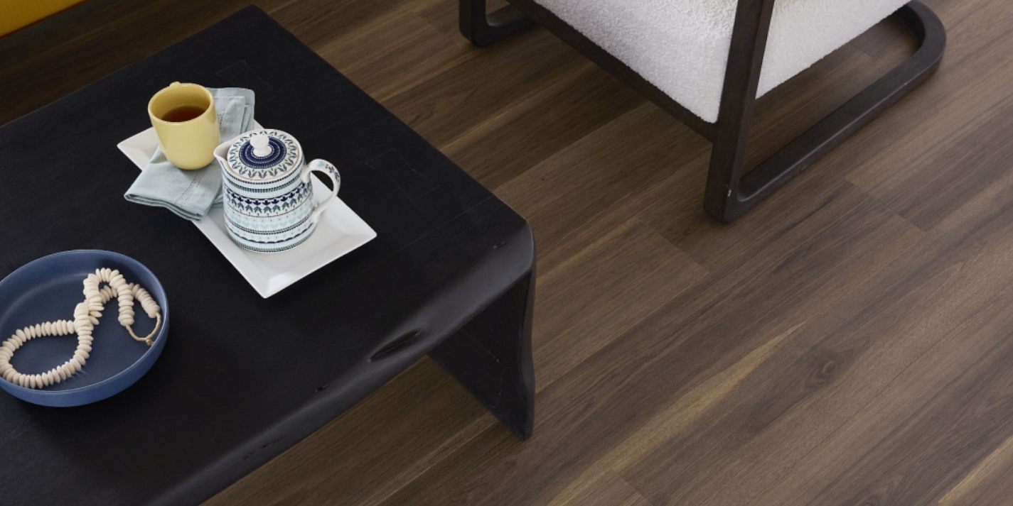 Dark Pergo flooring in a seating area with a black coffee table and white chair