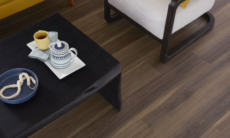 Dark Pergo flooring in a seating area with a black coffee table and white chair